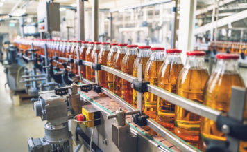 Conveyor belt, juice in glass bottles on beverage plant or factory interior, industrial manufacturing production line